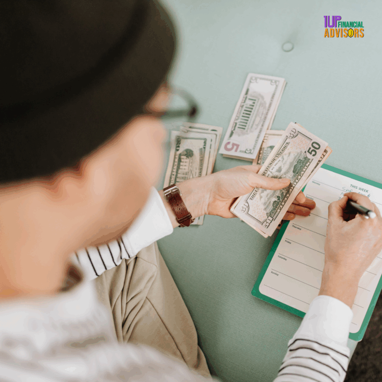 Content creator budgeting cash with a weekly planner, organizing expenses with $50 and $5 bills, seated casually with notepad on lap — 1UP Financial Advisors branding visible.